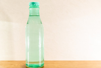 Colored glass bottles with natural water on light and illuminated background
