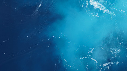 close-up wavy blue ocean surface, foam streaks on sea water