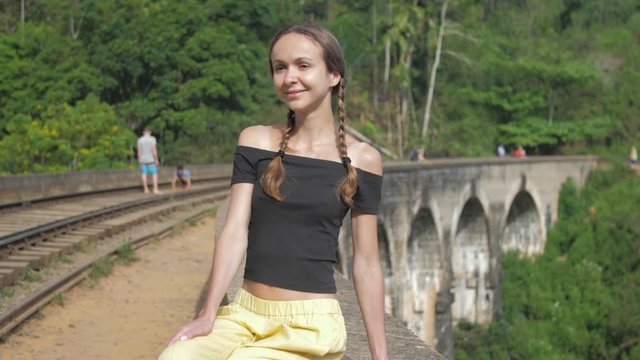 nice girl sits smiling on famous old bridge stretching against wildlife in tropical jungle slow motion closeup. Concept environment travel lifestyle