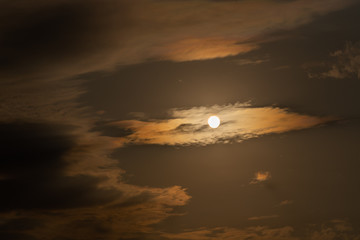 Dramatic late afternoon sky and sun between clouds forming a spiraling geometric figure