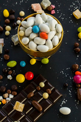 Traditional Turkish Hard Almond Candies designed on black surface with chocolate.Conceptual image of celebrations.