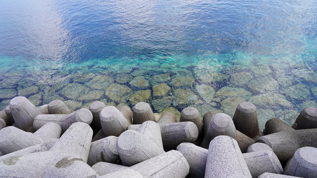 
breakwater consisting of tetrapods in the turquoise blue water of the ocean. clear clear sea water off the coast of a tropical island