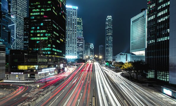 Light Trails On Road Amidst Buildings In City At Night