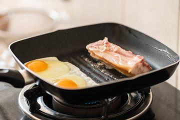 sunny side up fried eggs with bacon in hot pan