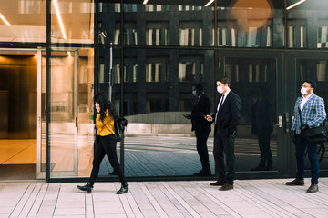 Business people with face masks standing in line outside office building