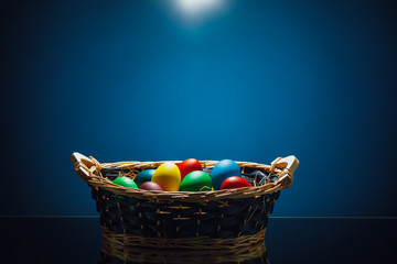 Easter color eggs in festive gift basket, blue background