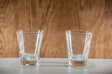 Glass cups on clear surface and woody background