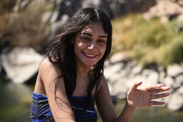 Portrait of young sexy brunette girl posing on a river beach
