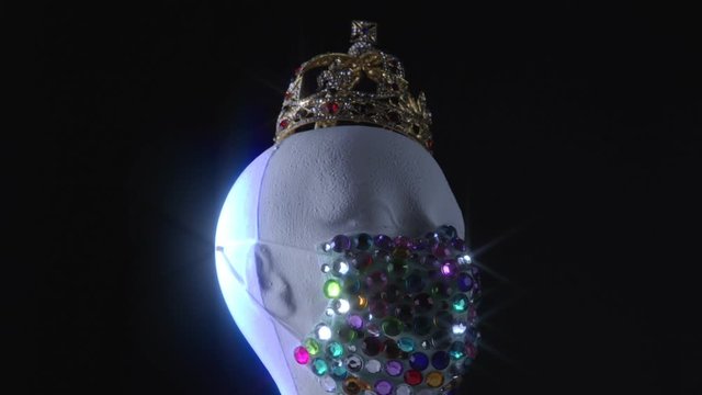 Urban medical mask and gold crown on the woman mannequin rotating. Kinky expensive diamond accessory for celebrity model during virus disease COVID-19  coronavirus pandemic self isolation.