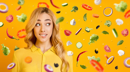 Attractive blonde lady biting her lip and vegetables flying in air, collage with free space