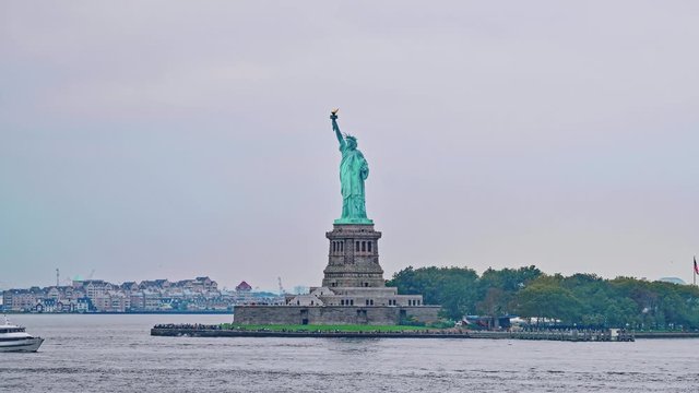 NEW YORK, USA - OCTOBER 2, 2018: Camera on board passes the Statue of Liberty on Liberty Island during the gloomy weather, designed by French Frederic Auguste Bartholdi and built by Gustave Eiffel.