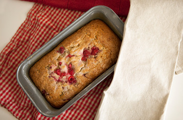 sweet raspberry bread freshly baked in a loaf pan with dish towels