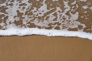White foam on a sandy beach. Copy space.