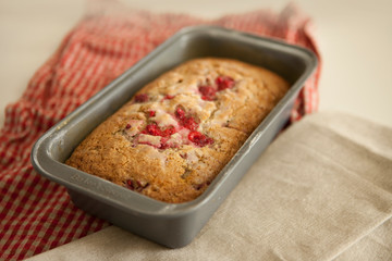 sweet raspberry bread freshly baked in a loaf pan with dish towels