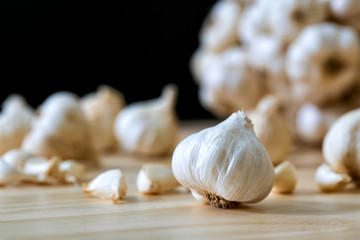 Closeup of Garlic bulbs and cloves on wooden table on black background..