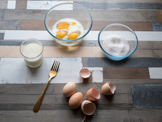 process of making omelet from natural eggs and products. Milk, salt, eggs. Cup for whipping omelet. Fork and knife. Frying pan and oil