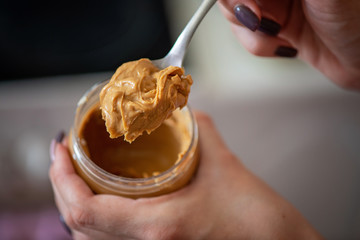 Peanut butter on a spoon and in a jar