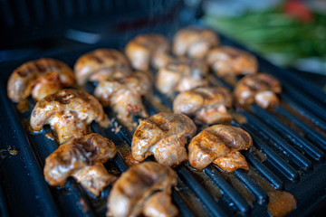 Grilling champignon mushrooms on an electric grill at home