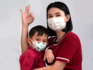 Portrait of mother and son are showing OK sign and wearing protective mask trying to protect from...