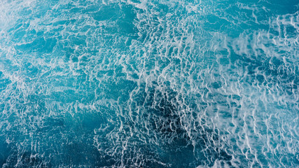 Sea blue water surface background, foam streaks on natural ocean background. Aerial view of the ocean
