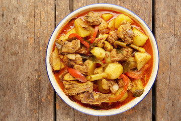 Top view of spicy chicken curry in bowl on wooden table