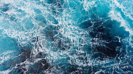 background pacific ocean during a typhoon, bright blue color of a sea splashing wave, texture of sea foam. abstraction of ripped water waves in the ocean in a storm sunlight. turbulent ocean © Artem