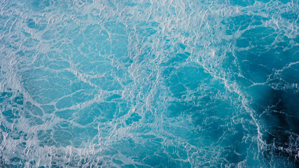 Sea blue water surface background, foam streaks on natural ocean background. Aerial view of the ocean