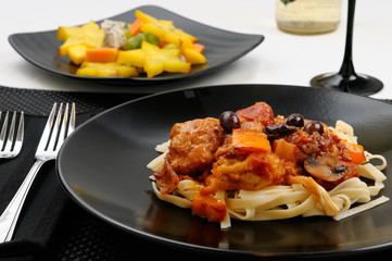 Close up of table setting with plate of Chicken Marengo with fruit salad and white wine