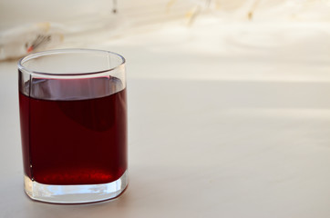 one glass glass with currant juice on a sunny windowsill