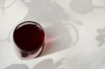 one glass glass with currant juice on a white background with a shade view from above