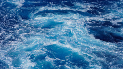 Fototapeta na wymiar Abstraction of sea foam in the ocean. Dark water stormy waves turquoise pacific ocean water on a sunny day
