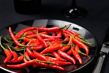 Mass of red hot Chili Peppers on a black plate and table setting