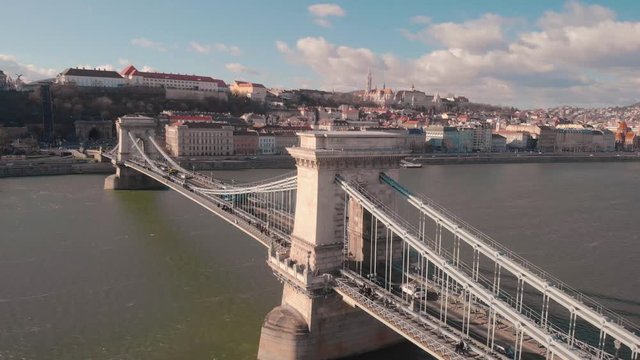aerial rotating drone shot around the Chain Bridge in Budapest with the Castle and Mathias Church and a tunnel in the background on a sunny day