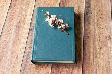 An open book lies on the table. Flowering tree branch on a book. Spring Flower.