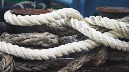 Anchor rope in the port, ship mooring tool. Close-up of textile rope on a pier. bollard in seaport. new white industrial rope