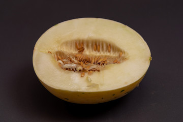 Melon fruit (Cucumis mello L.) halved on a dark background