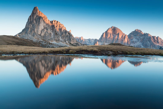 View of famous Dolomites mountain peaks glowing in beautiful golden morning light at sunrise in summer, South Tyrol,Italy Ra Gusella and Giau pass reflection in lake. Famous best alpine place in Alps. © Michal