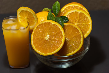 Navel oranges sliced in glass bowl and glass of orange juice