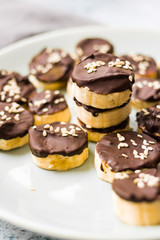 Banana slices in melted chocolate with sesame seeds. Vegan sweet healthy dessert.