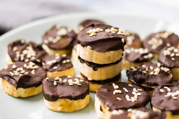Banana slices in melted chocolate with sesame seeds. Vegan sweet healthy dessert.