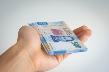 Hand holding a deck of mexican pesos of 500