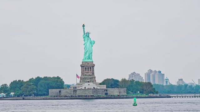 Statue of Liberty on Liberty Island during the gloomy weather in New York. Police department speedboat passing by.