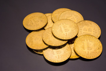 Golden coins with bitcoin symbol on a black background.