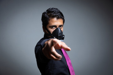 adult businessman pointing out protecting himself with a pandemic from the coronavirus in Mexico with a black background and a black shirt and a wine-colored tie