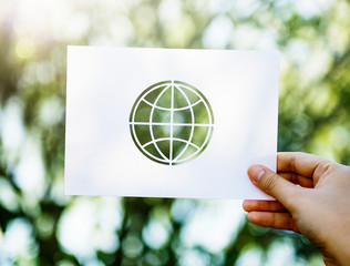 Hand showing perforated globe shape paper on green nature background