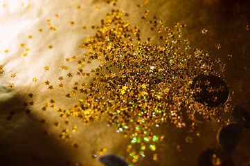 abstract gold shiny stars on a gold sheet of foil paper