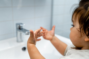 Close up of baby washing hands with liquid soap in the bathroom. Personal hygiene. Covid-19 prevention