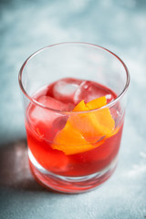 Red traditional old fashioned cocktail with orange zest on the rustic background. Selective focus. Shallow depth of field.