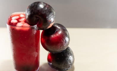 Plum juice (Prunus sp.) Served in a glass with ice and fresh fruits