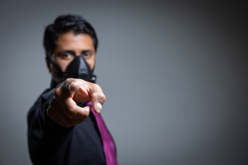 point person protecting himself with a pandemic mask from the coronavirus in Mexico with a black background and a black shirt and wine color tie